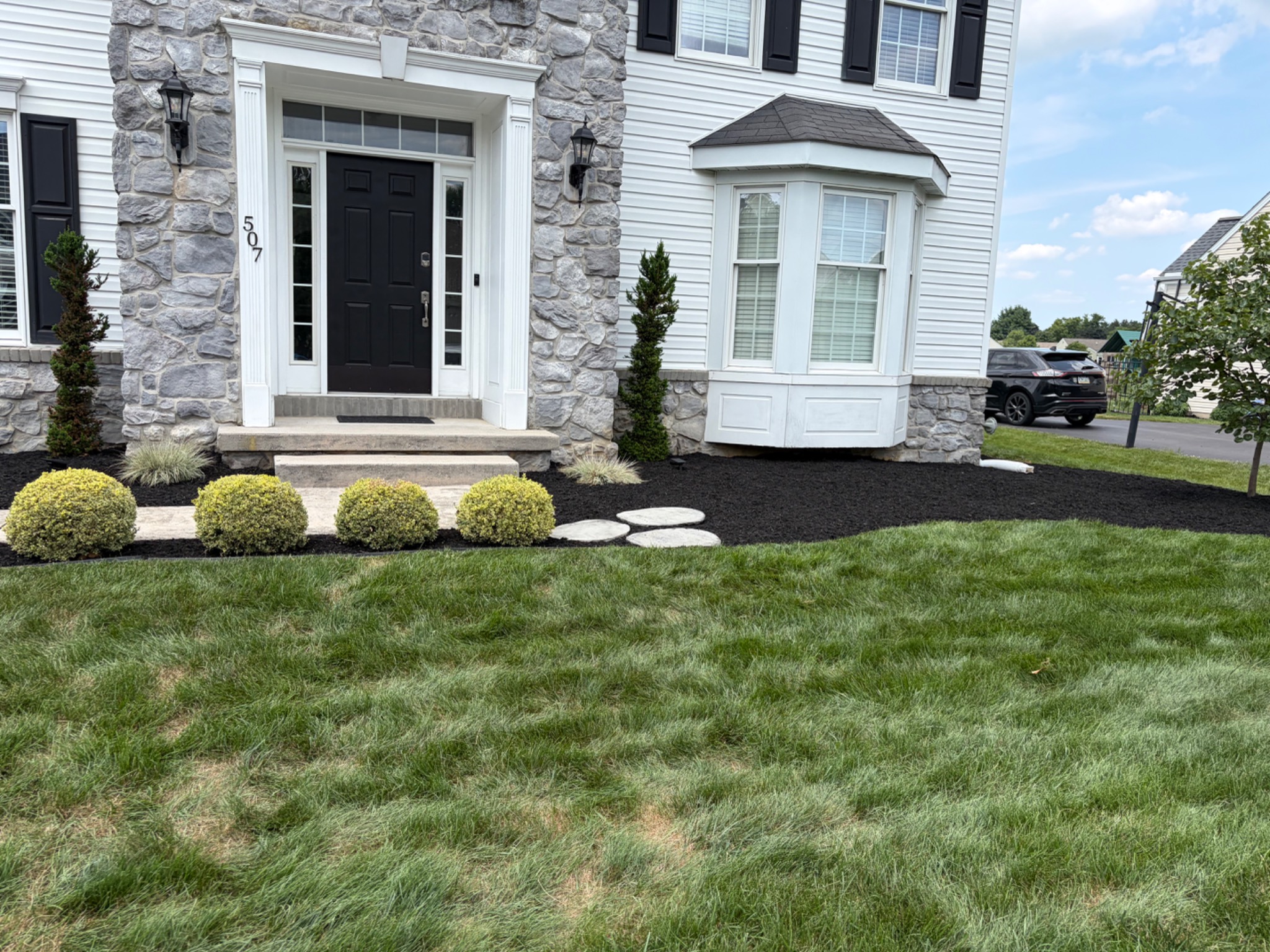 Fresh black mulch and curved bed edges across a home's front landscape