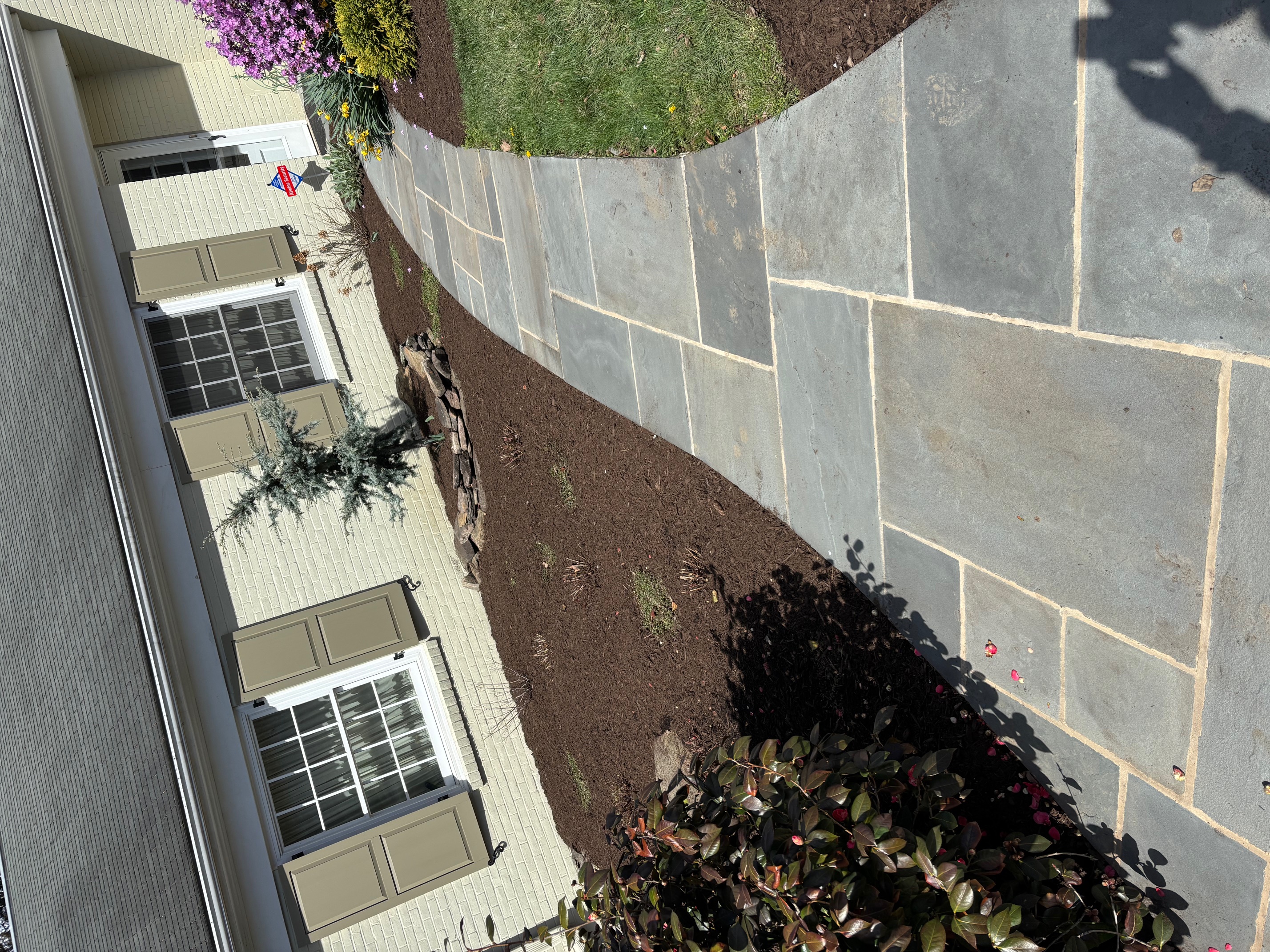 Stone walkway bordered by fresh mulch and spring planting beds