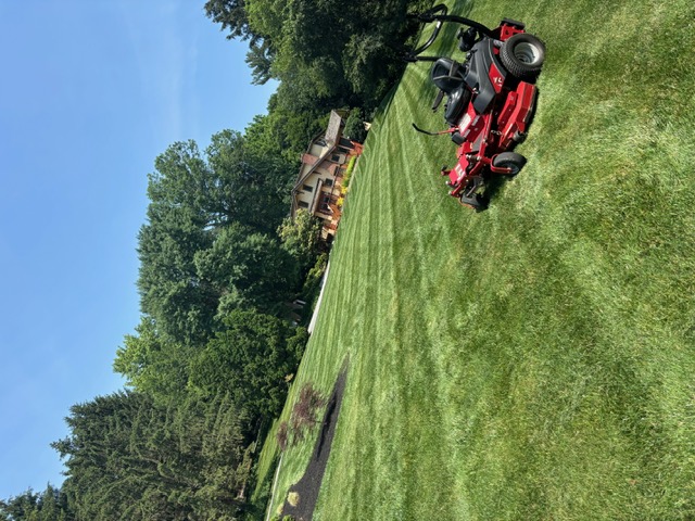 Striped lawn with a riding mower at a residential property